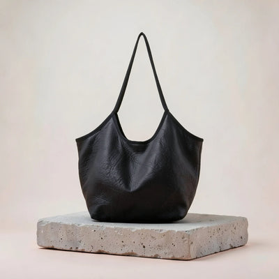 Black soft slouchy hobo bag resting on a stone plinth